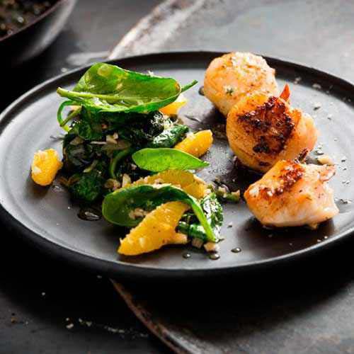 Dipped scallops with young spinach, nuts and oranges